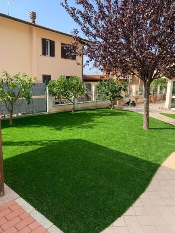 Prato sintetico su retro cortile con piante