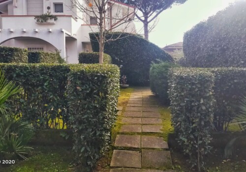 Villetta a schiera con vialetto in pietra e siepi verdi